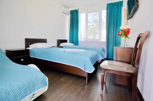 古达乌塔Family Resort Bambora的一间卧室设有两张床、一把椅子和一个窗户。