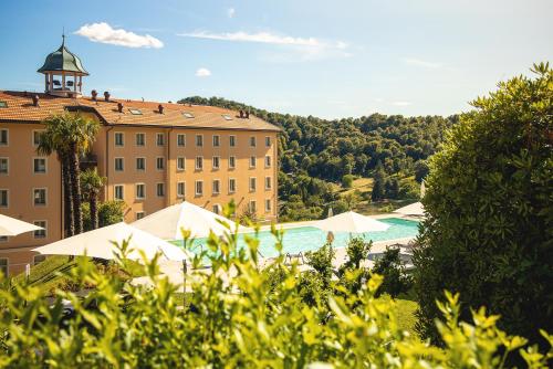 卡迪马里奥Kurhaus Cademario Hotel & DOT Spa - Ticino Hotels Group的一座带游泳池的度假村,位于一座建筑前