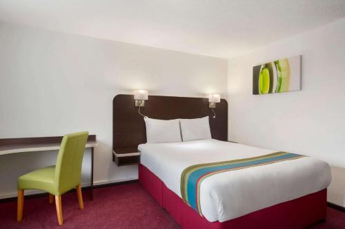 波特斯巴伦敦南米姆斯戴斯酒店 - 波特斯巴店的酒店客房,配有一张床和一把绿色椅子