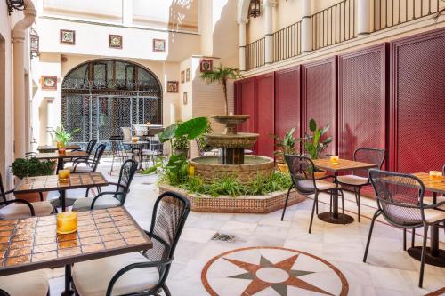 塞维利亚H10柯里基多精品酒店 的一间带桌椅的餐厅和一个喷泉