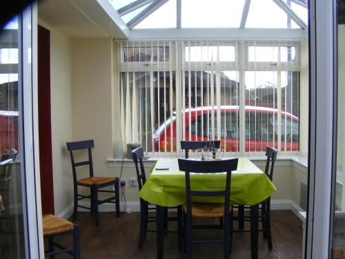 LennoxtownDingieshowe Cottage的一间带桌椅和窗户的用餐室