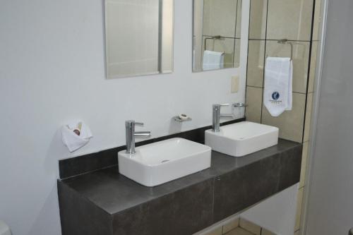 瓜达拉哈拉Hotel Suites del Real的浴室设有2个盥洗盆和镜子,位于柜台上