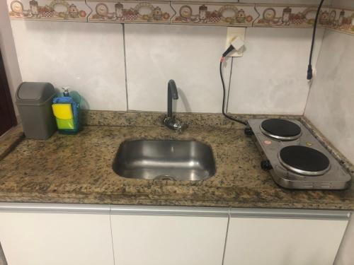 弗洛里亚诺波利斯Apartamento em Floripa -Muito próximo ao Aeroporto的厨房柜台设有水槽和炉灶。