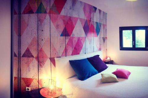 普隆比埃莱班Gîte de charme : A la volette的一间卧室配有一张带蓝色和粉红色枕头的床