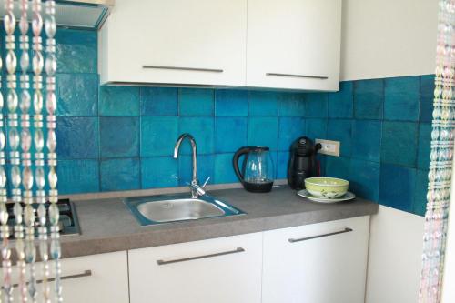莫诺波利Le casette的厨房设有水槽和蓝色瓷砖墙。