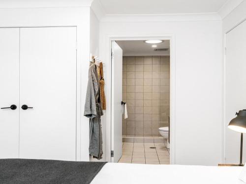 拜伦湾Le Viti的一间带白色墙壁的卧室和一间带卫生间的浴室