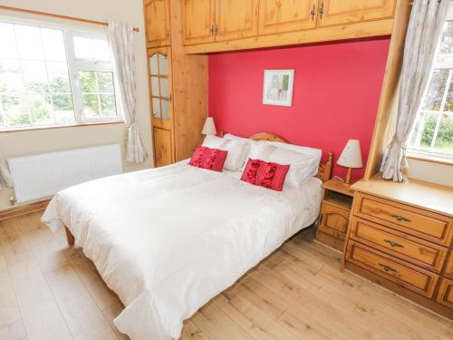 CollooneyClodagh's Cottage的卧室配有白色的床和红色的墙壁