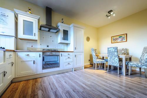 卡迪夫De Courceys Manor Suites & Cottages的厨房配有白色橱柜和桌椅