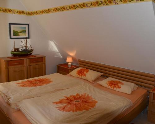 奥埃费努姆Ferien unterm Reetdach Whg 01的一间卧室配有两张带橙色枕头的床