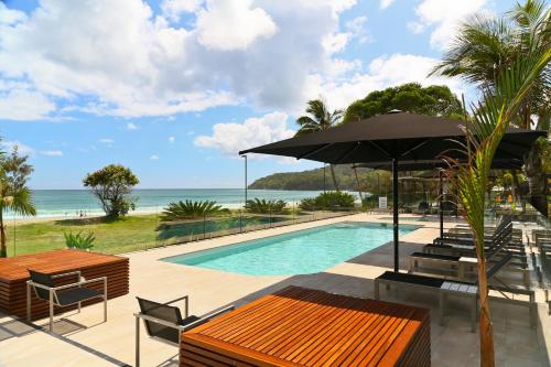 努萨角Seahaven Noosa Beachfront Resort的一个带桌子和遮阳伞的游泳池