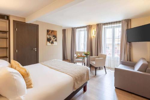 贝尔福Best Western Plus Hôtel Belfort Centre Gare的酒店客房配有床、沙发和桌子。