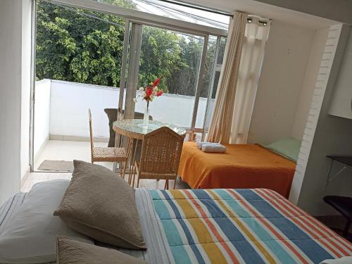 利马Monterrico Suites Hotel的一间卧室配有一张床铺和一张桌子,并设有一个阳台