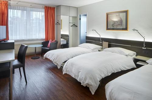 巴塞尔商业酒店的酒店客房设有三张床和一张书桌