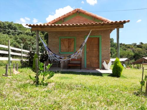 圣托梅-达斯莱特拉斯Chalés e Camping Taquaral的庭院内的小房子,配有吊床