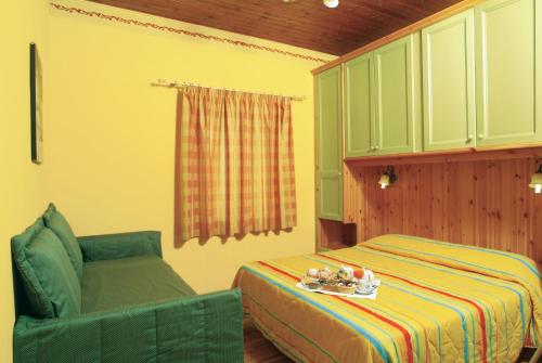 圣马西莫罗西亚特罗酒店的一间卧室配有一张床和一把绿色椅子