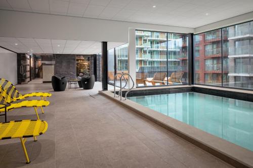 阿姆斯特丹Inntel Hotels Amsterdam Landmark的一座游泳池,位于一座带黄色椅子的建筑中