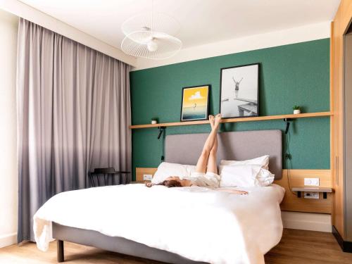安锡阿纳西中心阿德吉奥公寓式酒店的躺在床上,腿放在空中的人