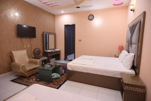 木尔坦Hotel Shaheen Continental Multan的一间卧室配有一张床、一把椅子和电视。