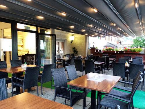 巴特欧波Hotel Restaurant Toscana的一间带木桌和桌椅的餐厅