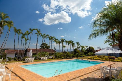 圣安东尼奥杜雷特VOA Mirante Do Café的棕榈树度假村的游泳池