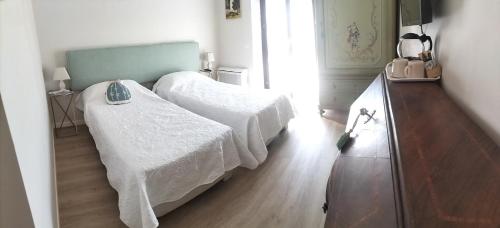 蒙扎Al Giardino Segreto的一间卧室配有两张带白色床单的床,铺有木地板