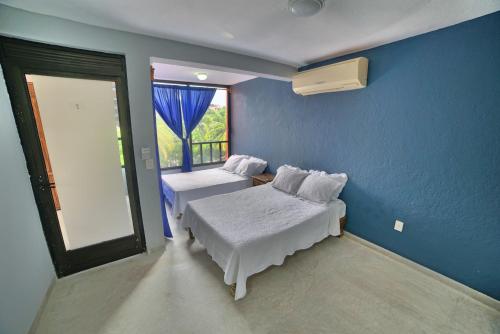 锡瓦塔塔内霍Zihua Mia Hotel Boutique的蓝色的客房设有两张床和窗户。