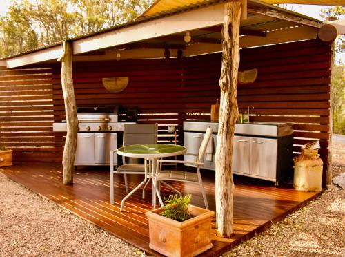 Boonah克车河边豪华帐篷的户外厨房,在木甲板上配有桌子