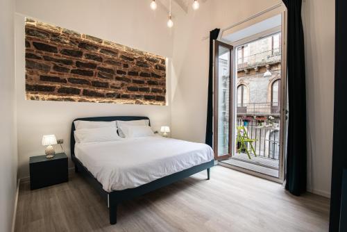 卡塔尼亚Il Moro Boutique Apartment的一间卧室设有一张床和砖墙