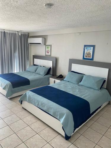 圣胡安Isla Verde Studio的卧室设有两张床铺,配有蓝色床单