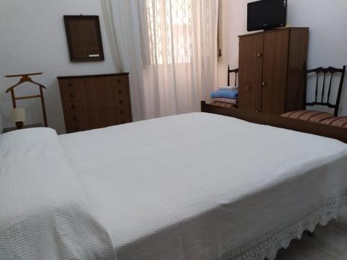 AssoroCasa ad Assoro, al centro della Sicilia的卧室配有白色的床和电视。