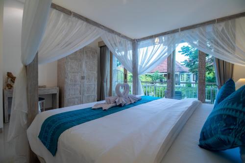 沙努尔Sayang Sanur Duplex的卧室配有白色床和粉红色毛巾