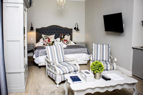 博福特西French Karoo Guesthouse的一间卧室配有一张床、两把椅子和一张桌子