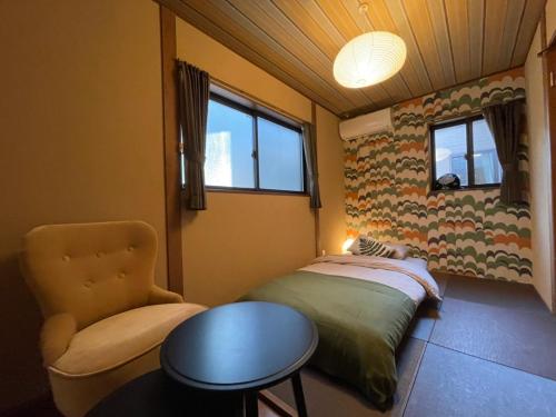 京都Guesthouse Nobi的一间卧室配有一张床、一把椅子和一张桌子