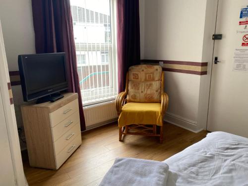 Thatto HeathPark View Hotel and Guest House的一间卧室配有一张床、一台电视和一把椅子