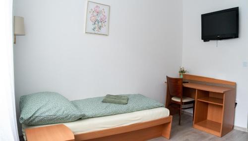 日利纳Ubytovanie SASINKOVA的一间小卧室,配有一张桌子、一张床和一台电视