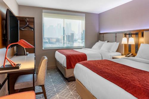 皇后区Comfort Inn JFK Airport的酒店客房设有两张床、一张书桌和一个窗户。