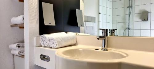 施韦青根eXo Square Heidelberg/Schwetzingen - by SuperFly Hotels的浴室配有盥洗盆、镜子和毛巾