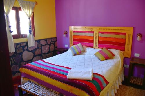 普尔马马尔卡Hostal Paseo de los Colorados的一间卧室设有一张紫色墙壁的大床