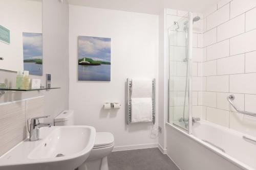 奥本西部大酒店的白色的浴室设有盥洗盆、卫生间和淋浴。