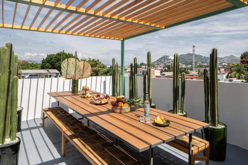 瓦哈卡市HOLT - Villa Noria - La Casa del Barro Verde的仙人掌阳台的木桌,带水果