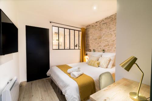 尼姆Appartement Cosy Nîmes-Centre的一间卧室配有一张床和一张带台灯的桌子