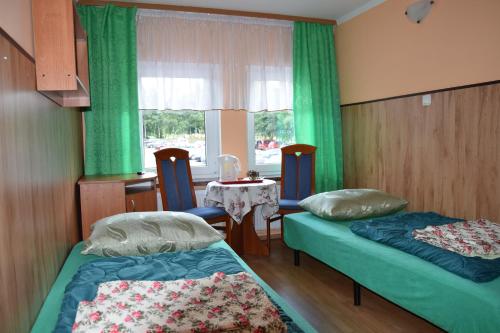 卡尔洛夫Ośrodek Wypoczynkowy Pod Szczelińcem的客房设有两张床、一张桌子和一扇窗户。