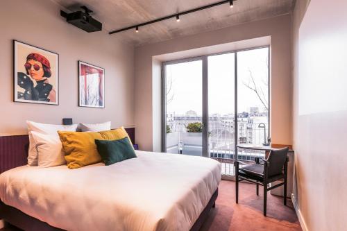 巴黎Hotel Paradiso的卧室配有床、椅子和窗户。