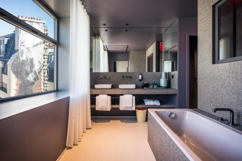 巴黎Hotel Paradiso的带浴缸、两个盥洗盆和窗户的浴室