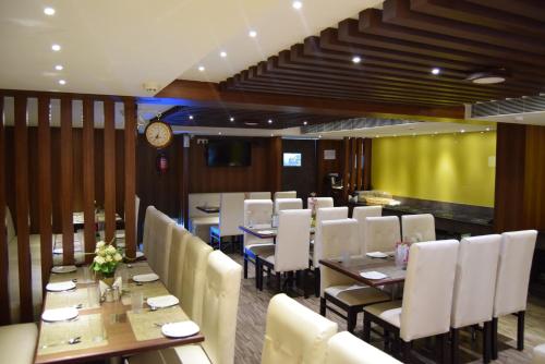 钦奈Thiviyam Airport Hotel的一间带桌椅和时钟的用餐室