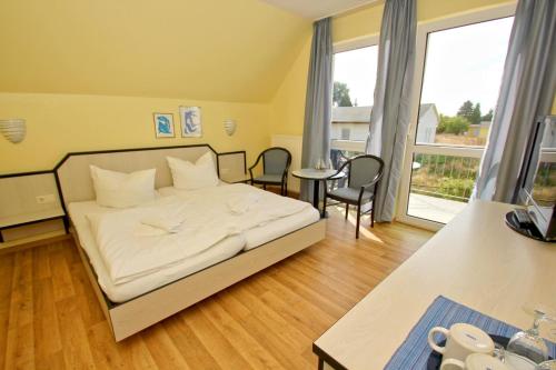 洛布F-1010 Strandhaus Mönchgut Bed&Breakfast DZ 33 Balkon, strandnah, inkl Frühstück的卧室配有白色的床和桌椅