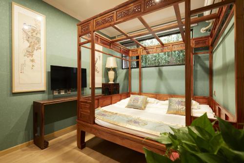北京北京荣府老宅四合院精品酒店 的一间卧室配有一张天蓬床和一台电视机