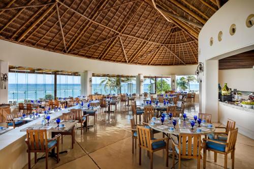 普拉亚卡门玛雅里维埃拉大酒店（全包）的餐厅设有桌椅,背景为大海