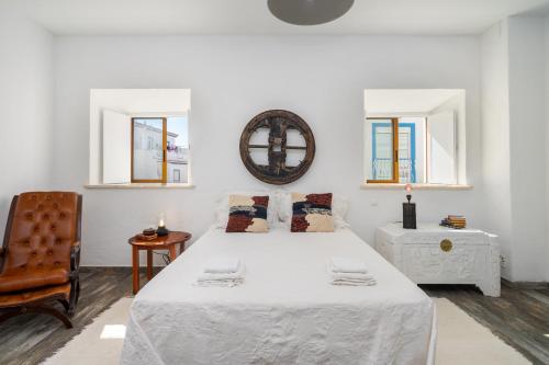 埃斯坦巴Casa Celeiro的白色卧室配有一张大床和椅子