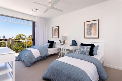 黄金海岸The Beach Houses Holiday Villas的一间卧室设有两张床、一张桌子和一个窗口。